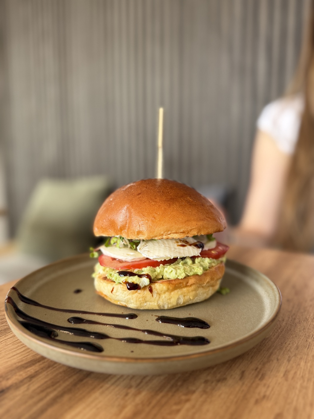 Burger s kuřecím masem a avokádem na talíři